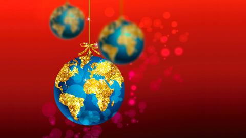 Blaue Weihnachtsbaumkugel mit goldener Weltkugel vor rotem Hintergrund