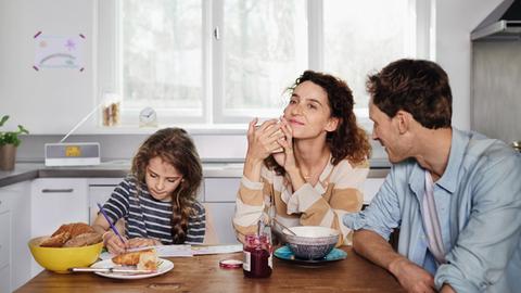 Eine Familie sitzt in der Küche und hört Radio
