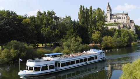 Lahn mit Ausflugsschiff, im Hintergrund die Lubentius-Basilika im Stadtteil Dietkirchen. 