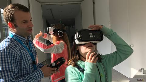 Zwei Mädchen mit Virtual-Reality-Brillen, zusammen mit hr-Mitarbeiter Simon Binnenmarsch