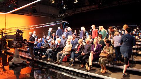 Zahlreiche Komparsen sitzen als Publikum im Fernsehstudio.