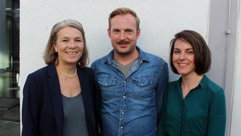 Die Komparsen Ethel Dadam, Martin Schlemmer und Pauline Meignan lächeln in die Kamera.
