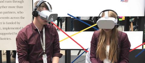 Ein Mann und eine Frau probieren die VR-Brillen aus 
