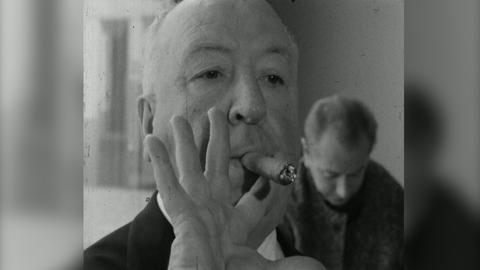 Alfred Hitchcock raucht eine Zigarre.