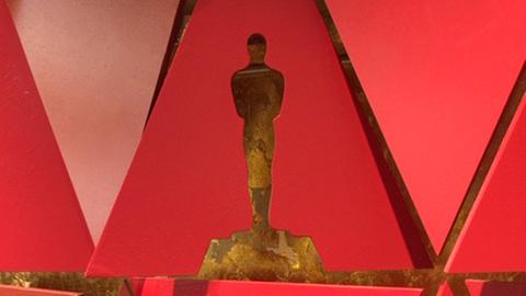 Rote Dreiecke ergänzen sich zu einer Wanddekoration. Im oberen Dreieck ist die Form einer Oscar-Trophäe ausgeschnitten.