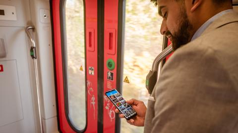 Ein Mann fährt in der Bahn und nutzt die ARD Audiothek.