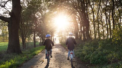 Mädchen fahren mit dem Fahrrad durch den Wald 