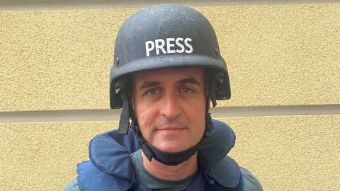 Marc Dugge in schusssicherer Weste und Helm, auf dem "Presse" steht
