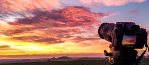 Bunter Himmel, im Vordergrund eine Spiegelreflexkamera.