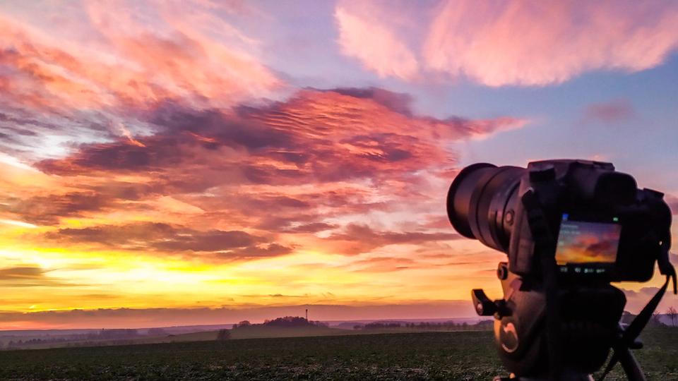 Bunter Himmel, im Vordergrund eine Spiegelreflexkamera.