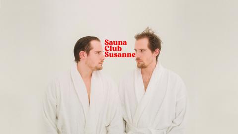 Key Visual von Saunaclub Susanne: Die beiden Hosts stehen sich im Bademantel gegenüber