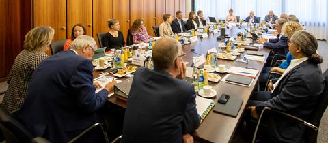 Mitglieder des Verwaltungsrats sitzen in einem Konferenzraum rund um einen großen Konferenztisch
