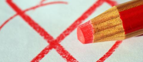 Roter Stift und gemaltes Kreuzchen auf einem Zettel