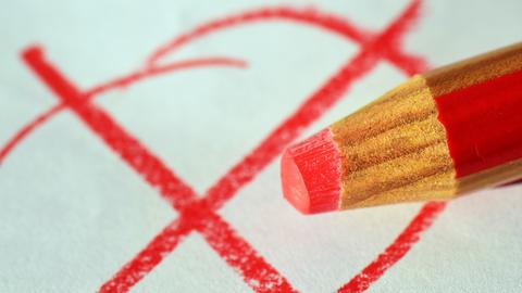 Roter Stift und gemaltes Kreuzchen auf einem Zettel